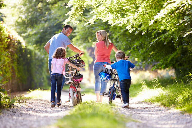 A family with bikes walking along a nearby park trail